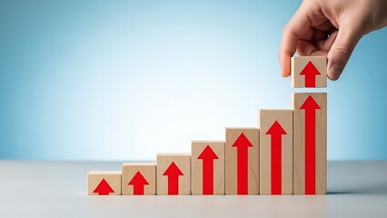 Hand arranging wooden blocks with red arrows pointing upwards symbolizing continuous growth and progress in a business or financial context with a clear and achievable goal.