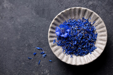 Dried blue cornflower petals, herbal tea. Dark grey background. Close up. Copy space. Top view.