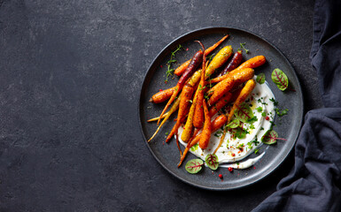 Roasted carrots salad with yogurt. Dark grey background. Copy space. Top view.
