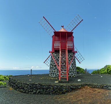 Traditional red windmill Moinho de S&atilde;o Jo&atilde;o made of volcanic stone in front of a clear blue sky, Sao Joao, Pico Island, Azores, Portugal