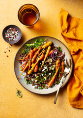 Warm lentil salad with carrot, arugula and feta cheese. Yellow background. Close up. Top view.