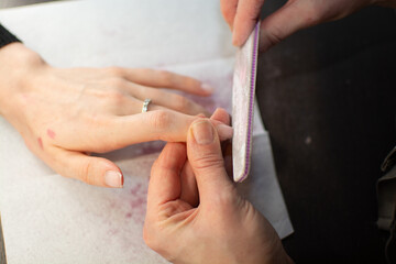 A nail technician files a clients nails with a nail file, professional nail care
