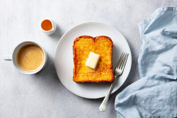 Cozy breakfast. French toast with butter, served with coffee and maple syrup. Grey background. Top view.