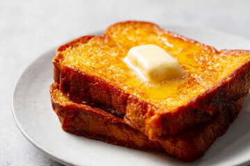 French toast slices with melting butter. Grey background. Close up.