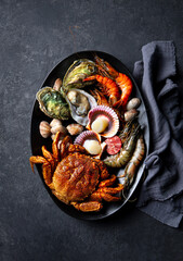 Exquisite seafood platter: crab, oysters, scallops, elegant dark backdrop, gourmet dining. Top view.