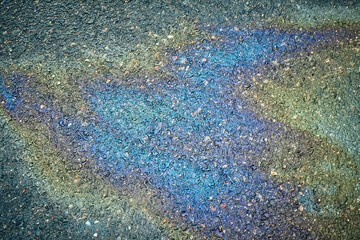 An iridescent oil slick creates a colorful pattern on wet asphalt.