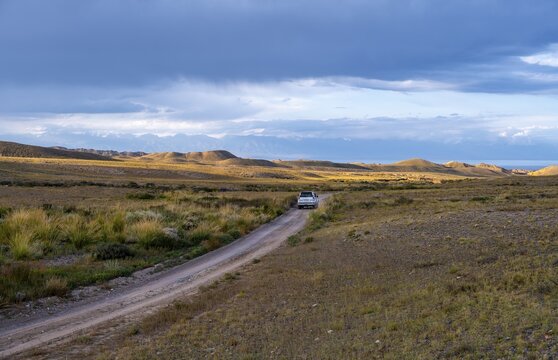 Off-road vehicle on a rural road under a cloudy sky in nature, Kyrgyzstan