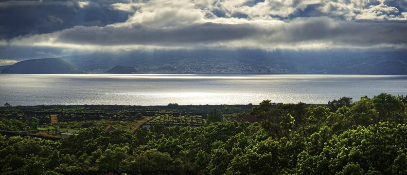 View of the island of Faial and the town of Horta with sun rays breaking through the clouds, Horta, Faial, Azores, Portugal