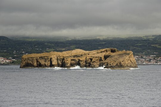 The remote rocky island 'Iieu Deitado' off a coastline of Pico under a cloudy sky, Iieu Deitado, Iieu em Pe, Horta, Faial, Azores, Portugal