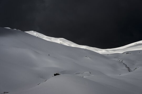 Extensive plateau with snow-covered mountains in the background and dramatic sky, Berlinger K&ouml;pfle, Ritzlern Kleinwalsertal, Vorarlberg, Austria