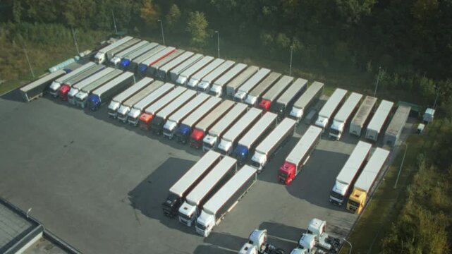 Industrial truck lot with staff preparing vehicles, Aerial view of truck depot showing organized fleet and workers