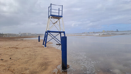 Lifeguard tower standing on beach during cloudy day
