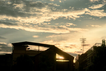 Silhouette of a building and radio tower against a golden sunset sky in Bangkok, Thailand