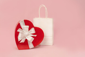 A holiday backdrop with a heart-shaped cardboard box with a bow, a gift bag on a pink background. Great for holidays, Mother's Day, weddings, or Valentine's Day.