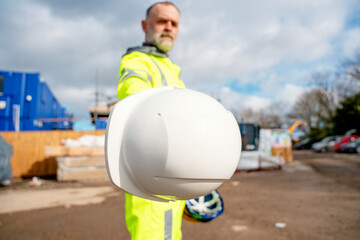 Concept of standard safety PPE to be used on construction site. Builder demonstating hard hat helmet for head protection