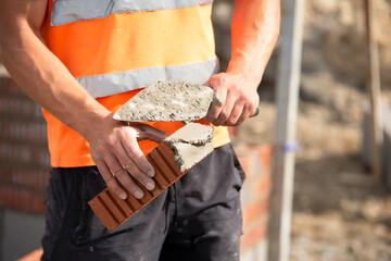 Bricklayer laying bricks for wall construction on building site