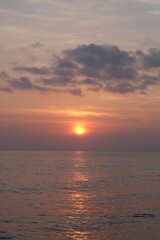 Fototapeta premium Golden Sunset Over Water with Dramatic Clouds and Reflections.