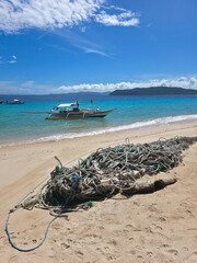 rope on the beautiful sand beach on sunny day near  small local boats on turquoise tropical wave sea near philippines islands