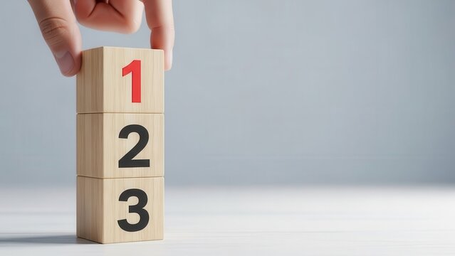 Hand placing wooden block with number one on top of a stack to indicate priority or ranking.