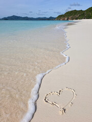 beautiful white sand beach with drawing heart on it on sunny day near turquoise tropical wave sea. philippines islands. vertical