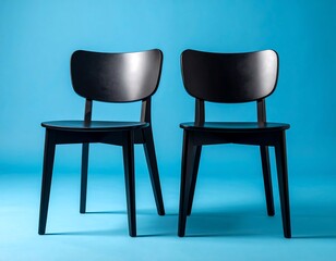 Two black wooden chairs against a vibrant blue backdrop