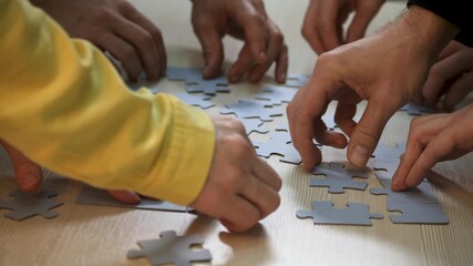 Assemble puzzle pieces with hands in cooperative teamwork collaboration between child and adult for education and strategy practice around tabletop promoting problem solving and family bonding - Powered by Adobe