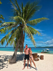 young love couple holding a red watermelon near their faces like smile on the sunny white beach with turquoise sea in philippines islands