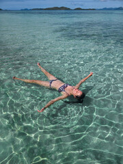 happy young woman in turquoise wave sea in philippines islands on sunny day. asia vocation. vertical