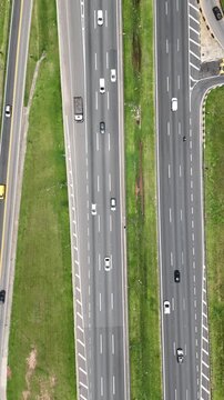 Vis&atilde;o a&eacute;rea de rodovia com m&uacute;ltiplas faixas e fluxo constante de ve&iacute;culos, evidenciando mobilidade urbana, infraestrutura vi&aacute;ria moderna e deslocamento di&aacute;rio em ambiente metropolitano.
