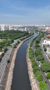 Imagem a&eacute;rea da Marginal Tiet&ecirc; na cidade de S&atilde;o Paulo SP, evidenciando o fluxo cont&iacute;nuo de ve&iacute;culos, a mobilidade urbana e a integra&ccedil;&atilde;o da via com &aacute;reas verdes e regi&otilde;es urbanizadas.