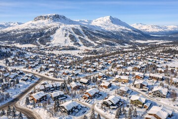 Snow-covered mountain village and scenic landscape with residential houses and towering snow-capped mountains in winter