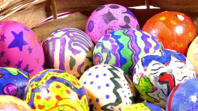 Colorful Easter eggs with various patterns sit in a wicker basket, bright and festive. Cheerful hues