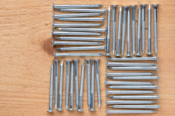 Group of new steel construction nails neatly arranged on a natural wood background. High resolution. Close-up.