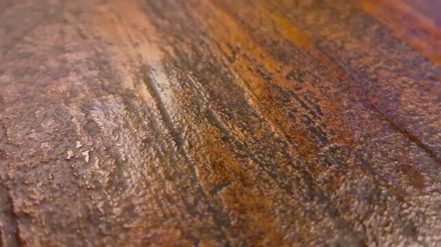 A macro close-up of a rough, weathered surface with layered brown and rust-colored textures, showing natural scratches and grain patterns suitable for abstract backgrounds.