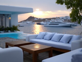 Elegant outdoor lounge area featuring white sofas and wooden tables, overlooking a serene waterfront with yachts and a beautiful sunset, creating a tranquil atmosphere for relaxation