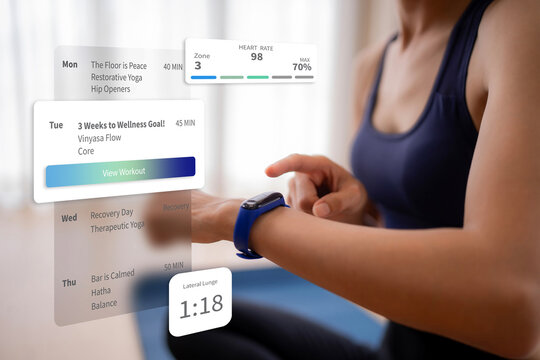 Adult woman using smartwatch tracking fitness metrics managing workout schedule yoga exercise achieving wellness goals at home