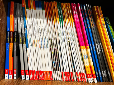 Assorted language textbooks on a wooden shelf featuring German and foreign language guides