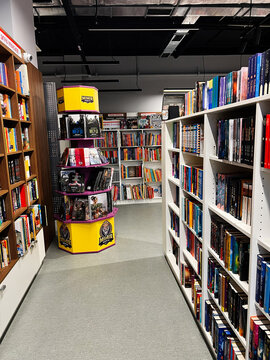Inside a bright bookstore with tall shelves and a yellow multi level display tower