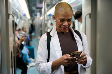 Woman smiling using phone on subway train
