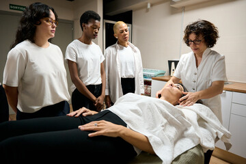 Educator demonstrating facial massage technique to students
