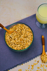 Bowl of dry rolled oats featuring a small wooden spoon ready for preparation alongside a glass of pale liquid suggesting milk or alternative beverage for healthy breakfast