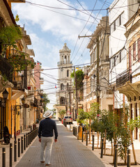 Man in Panama hat walking the street in Santo Domingo with Palacio Consistorial in the background