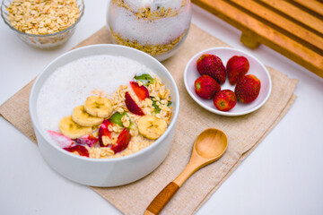 Delicious and healthy bowl of oatmeal cereal topped generously with fresh sliced bananas, vibrant strawberries, and kiwi pieces ready for a nutritious morning meal.