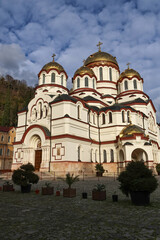 Fototapeta premium Sunny close-up of the main temple of New Athos Monastery under a blue sky. Bright daylight highlights Orthodox architecture, golden domes and historic spiritual heritage of Abkhazia.