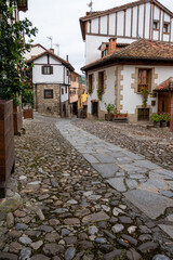 A cobblestone street with a house on the right in village of Potes. The street is narrow and has a brick walkway