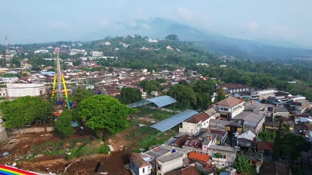 Aerial drone footage of Bandungan city in Semarang region, Java island, Indonesia, with Ungaran mountain in the background, at sunrise, in a cloudy atmosphere