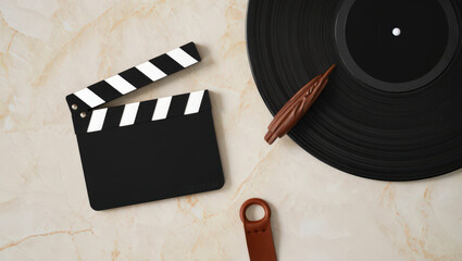 Artistic Still Life Composition Featuring a Clapperboard, Vinyl Record, Wooden Object, and Leather Accessory on a Marble Background for Creative Projects
