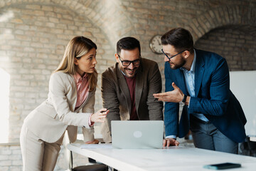 Confident business team sharing ideas and working together on a digital project in a bright workspace