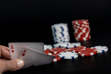 Hand holding two aces with poker chips
