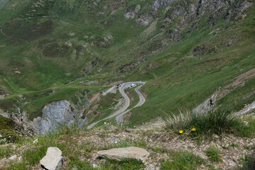 Winding Mountain Road Through Lush Green Hills With Scenic Switchbacks and Cars in View